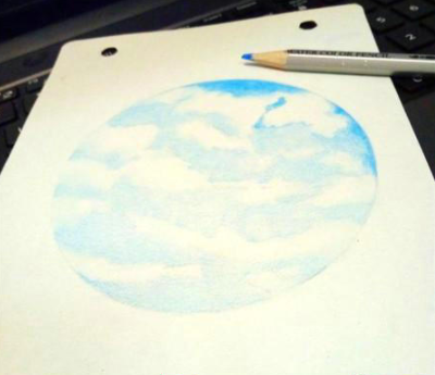 用蓝色彩铅在铺底色的基础上开始叠色加重天空的颜色,从靠近云朵的